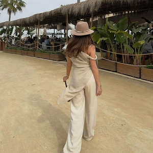 Dettaglio del top asimmetrico monospalla beige con spacco laterale e pantaloni lunghi