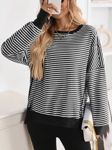 Close-up of black and white striped knit sweater with ribbed cuffs and drop shoulder