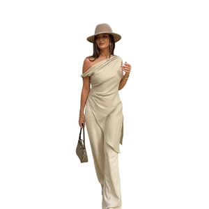 Dettaglio del top lungo asimmetrico monospalla beige chiaro con spacco laterale alto