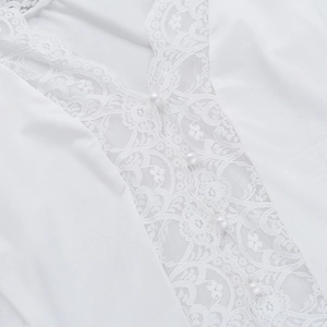 Close-up of white V-neck blouse with floral lace details and pearl buttons
