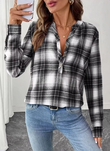 Close-up detail of black and white plaid V-neck shirt with metallic buttons and cuffs