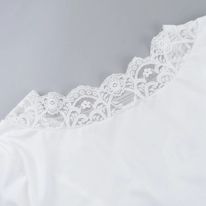 Detail of the white top featuring a scalloped floral lace neckline and soft fabric texture