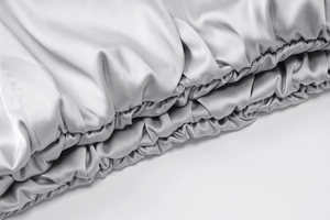 Detail of silver-grey silk fabric showing elasticated edges and smooth glossy texture