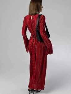 Detailed view of the red pleated dress showing back cutout and long waist tie feature