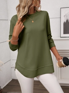 Detail of army green waffle knit texture and side slit hem on a loose casual long sleeve top