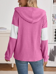 Detail of pink knitted hoodie showing white sleeve patchwork and ribbed texture on the back