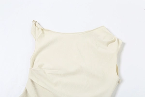 Dettaglio del top senza maniche beige con spalla annodata asimmetrica e trama a pieghe