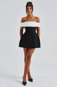 Detail of elegant off-shoulder neckline with white ruffles on black mini A-line dress