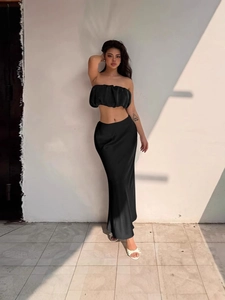 Elegant black two-piece set featuring off-shoulder ruffle crop top and high-waisted satin skirt
