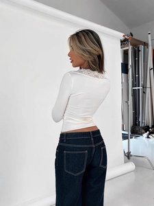 Women's slim fit long sleeve cream top with elegant lace trim and blue denim jeans