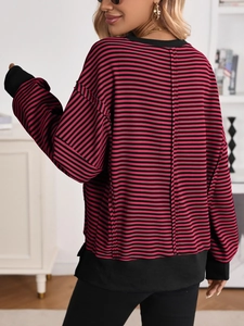 Close-up of women's oversized striped sweatshirt featuring black ribbed cuffs and hem