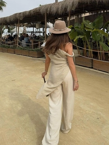 Top monospalla beige minimalista e pantaloni larghi in lino da donna in un resort estivo