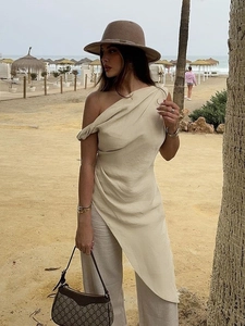 Elegante top lungo asimmetrico beige monospalla con pantaloni coordinati in spiaggia