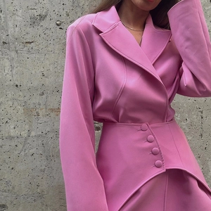 Detail of pink blazer set featuring lapel collar and unique buttoned high waist skirt