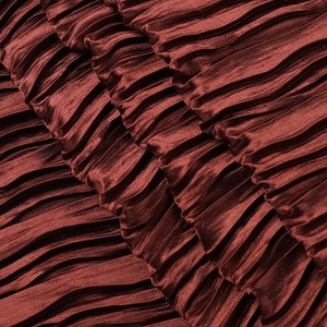 Gros plan sur un tissu plissé bordeaux avec une texture satinée élégante et brillante