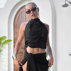 Detail of black halter top with pleated neck and high-slit skirt for sexy resort style