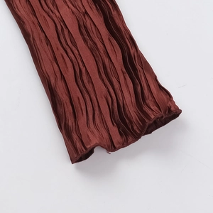 Détail du tissu satiné plissé rouge rouille avec une fine texture d'accordeon verticale