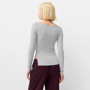 Detail view of the side slit and high-stretch knit fabric on this grey boat neck top