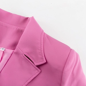 Detail view of pink suit jacket with notch lapel, size M tag and fine stitching lines