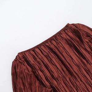 Détail d'une robe plissée bordeaux avec textures verticales et décolleté élastique