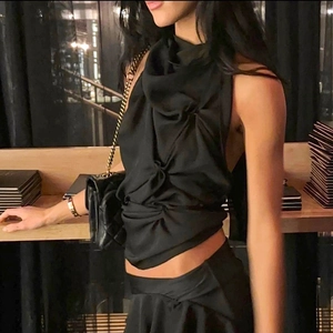 Detail of black halter top with ruching and quilted chain strap bag over shoulder