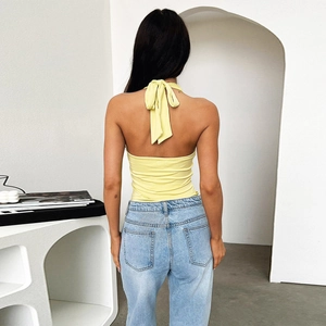 Detailed back view of a yellow halter top with a large bow tie and light blue jeans