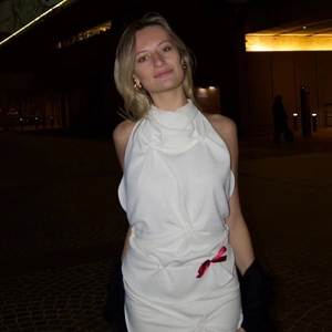 Detail of white halter neck dress featuring pleated texture and red bow accent