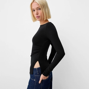 Detail view of black off-the-shoulder top with ruched waist and side slit details