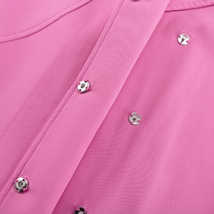Detail of pink fabric featuring a silver metal snap button and reinforced stitching