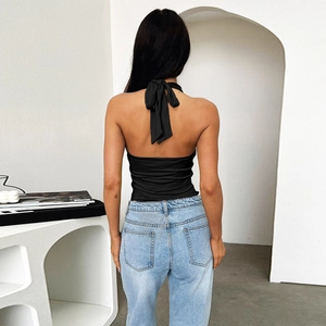 Back view of a black halter crop top with an oversized bow and open back design