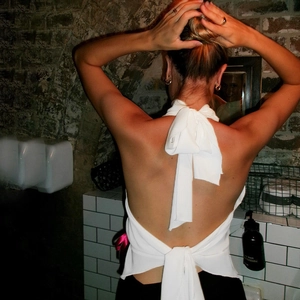 Detailed back view of white halter top with large bow tie-up and sexy open back design