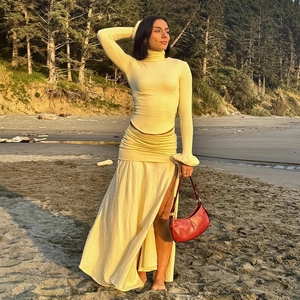 Detail of flared sleeves and curved hem on a light yellow slim fit spring knit top