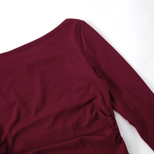 Detail of burgundy long sleeve top showing pleated side ruched fabric and soft knit texture