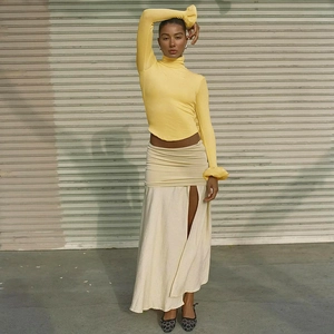 Detail of fitted bright yellow top with flared sleeves and white silk slit skirt