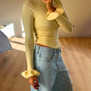 Close-up of ribbed knit top featuring flared ruffle cuffs and light yellow fabric detail