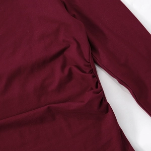 Detail of the side ruching and fabric texture on a burgundy off-shoulder top