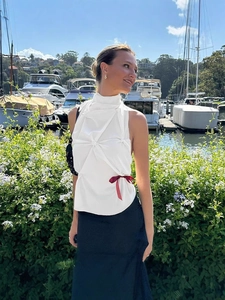 White halter neck sleeveless top with front pleats and a red bow accent in harbor