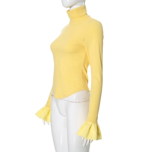 Detail of light yellow ribbed knit top featuring flared cuffs and a curved hemline