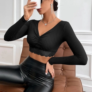 Detail view of black V-neck crop top with ribbed texture and floral lace trim at the hem