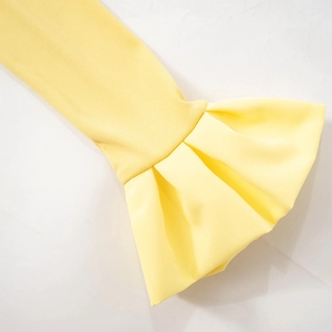 Detail of rib-knit sleeves with flared cuffs and fluid fabric on yellow top