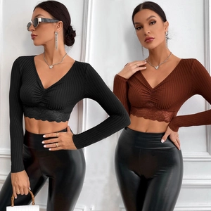 Detail of V-neck cropped long sleeve top featuring ribbed fabric and delicate lace trim edges