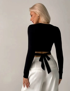 Detail van de zwarte crop top met lange mouwen en een modieus vetersluiting op de rug