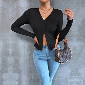 Dettaglio del crop top nero a maniche lunghe con scollo a V profondo e spacco sull'orlo