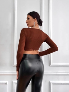 Slim fit brown V-neck crop top with lace hem and black leather leggings on model