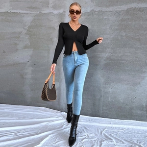 Dettaglio top in maglia nera aderente con scollo a V e spacco laterale e jeans blu