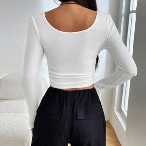 Détail du crop top blanc à manches longues en maille côtelée avec dos nu et col en U