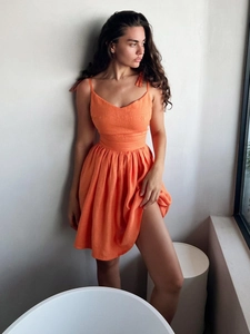 Detail of orange cotton dress with adjustable bow straps and textured fabric design