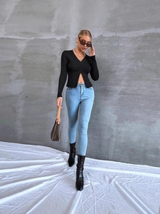 Top nero a maniche lunghe con scollo a V e spacco anteriore e jeans azzurri a vita alta