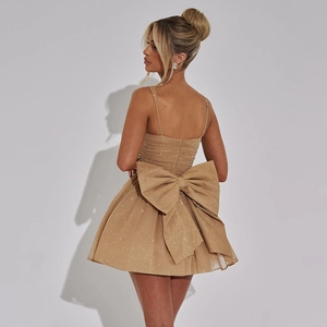 Detailed back view of champagne gold sequined dress with a large decorative bow