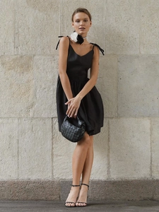 Detailed view of black backless mini dress featuring elegant bow tie adjustable straps